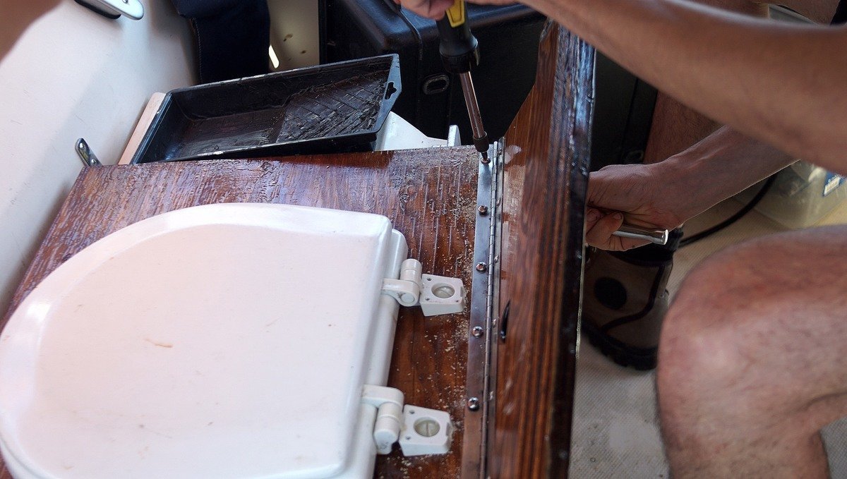 A photo of someone securing a piano hinge to two separate pieces of wood