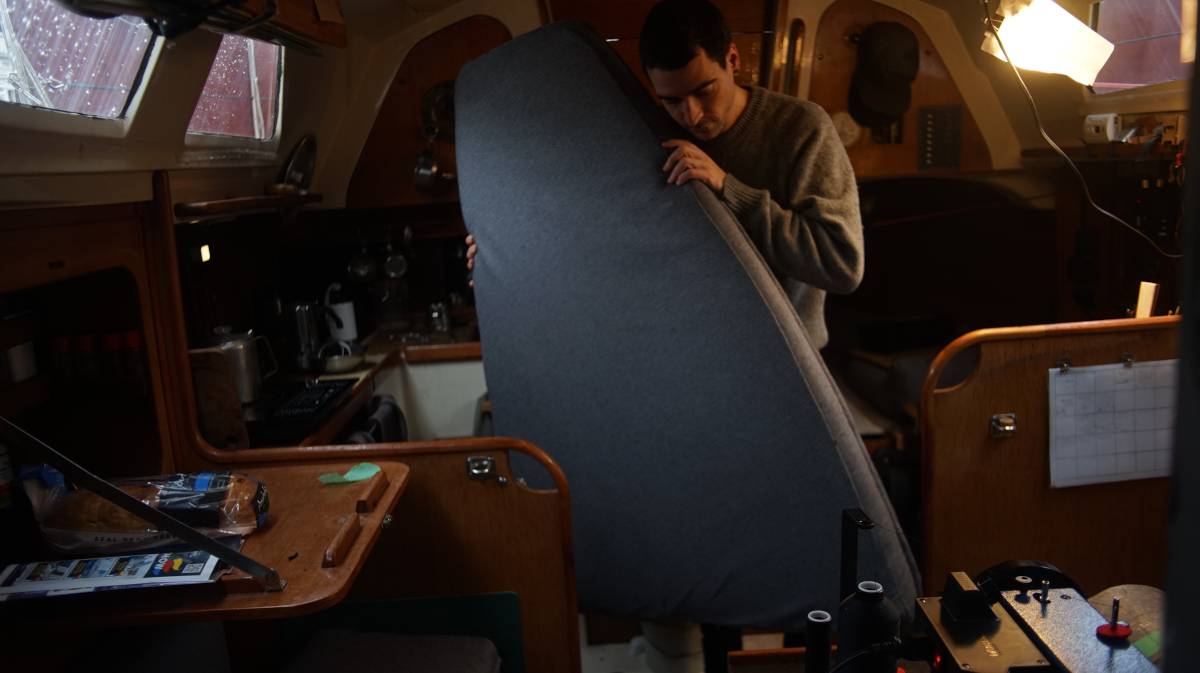 devine holding a tall newly-upholstered trapezoid cushion