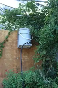 Figure 2: The existing 5-gallon storage bucket is the system's water source. The storage bucket is mounted to the retaining wall above garden beds.