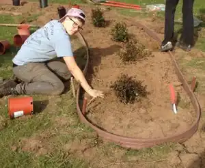 Figure-26: Student patting down soil after filling hole.