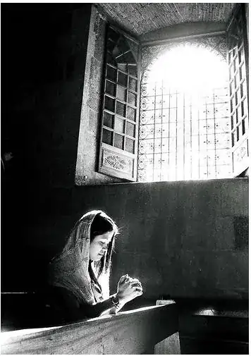 girl with mantilla praying in church