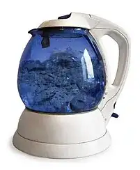 picture of electric kettle with a glass carafe perched on its electric base showing boiling water