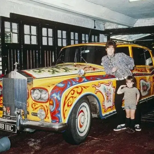 An image of a painted car in a garage with an adult male and a child