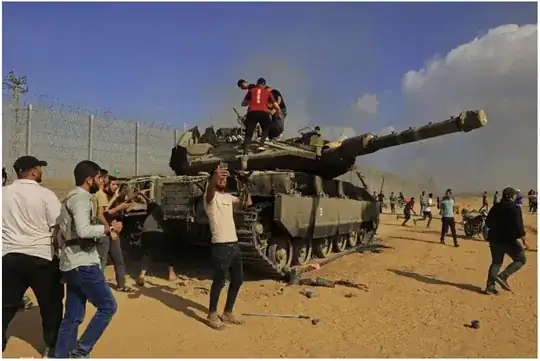 Palestinians take control of an Israeli tank after crossing the border fence with Israel from Khan Yunis in the southern Gaza Strip on October 7, 2023. Said Khatib/AFP via Getty Images