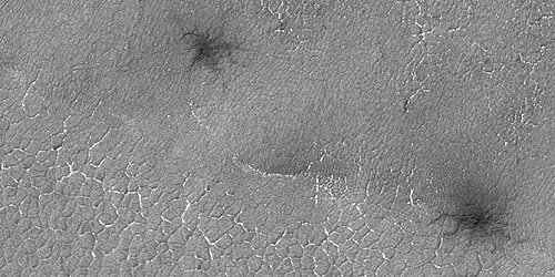 Close view of spider formations, as seen by HiRISE under HiWish program. The polygon shapes are channels caused by pressurized carbon dioxide going through cracks.  During the winter season, a slab of dry ice forms on the ground surface.  The surface contains cracks in the shape of polygons.  During certain times, CO2 under the ice becomes pressurized from sunlight penetrating the slab of dry ice.  As the gas moves around the channels become larger.