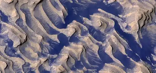 Close, color view of layers and dark dust on floor of Danielson Crater, as seen by HiRISE under HiWish program.  Boulders are visible in the image.