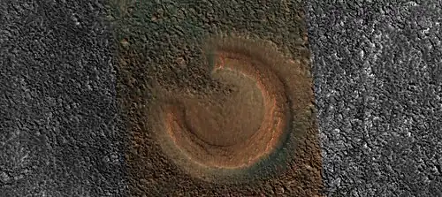 Close view of mud volcano, as seen by HiRISE.  Picture is about 1 km across.  This mud volcano has a different color than the surroundings because it consists of material brought up from depth.  These structures may be useful to explore for remains of past life since they contain samples that would have been protected from the strong radiation at the surface.