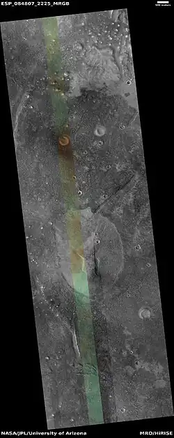Wide view of mud volcano, as seen by HiRISE.  The light-toned spots are the mud volcanoes.  They have a different tone than the surroundings  because they contain material brought up from depth.  These structures may be useful to explore for remains of past life since they contain samples that would have been protected from the strong radiation at the surface.  The colored strip is about 1&nbsp;km wide.