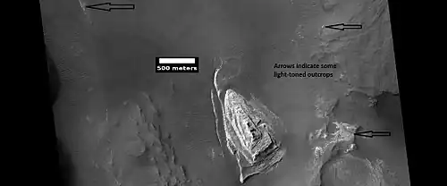 Light toned butte on floor of crater, as seen by HiRISE under HiWish program.  Arrows show outcrops of light toned material.  Light toned material is probably sulfate-rich and similar to material examined by Spirit Rover, and it once probably covered the whole floor. Other images below show enlargements of the butte.  Location is Margaritifer Sinus quadrangle.