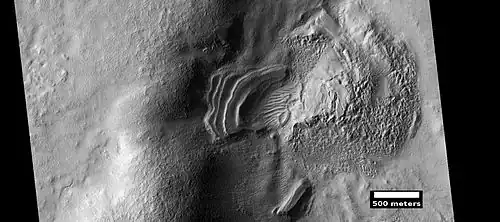 Layered feature that is probably the remains of a once widespread unit that fell from the sky, as seen by HiRISE under the HiWish program. Dipping layers are common in some regions of Mars. They may be the remains of mantle layers. Another idea for their origin was presented at 55th LPSC (2024) by an international team of researchers. They suggest that the layers are from past ice sheets.