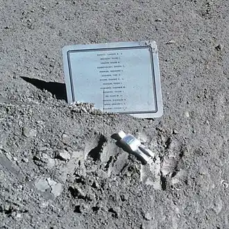 A small aluminum statue and a plaque on the lunar surface