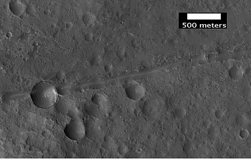Close-up of a possible fault in Mare Acidalium, as seen by HiRISE under the HiWish program.  A circle is drawn around crater to show that it may be off round because of movement of the fault.  Many other faults are in the region.