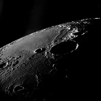 Oblique view facing southeast, from Apollo 11.  The large crater right of center is Theophilus, and Mädler is to its left.  Fracastorius is near the central horizon, and the white mountain on the horizon at right is part of the Rupes Altai.  The teardrop-shaped crater in the lower left is Torricelli.