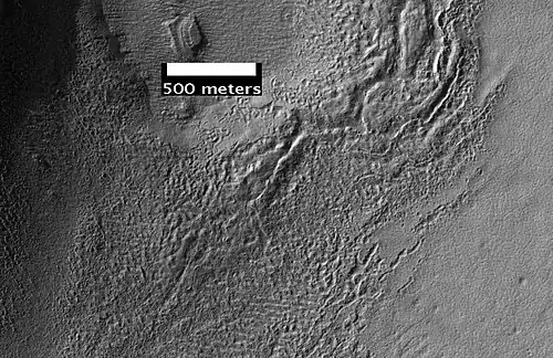 Surface of Debris Apron. There is also a feature similar to features in Red Rocks Park, Colorado.  Feature seems to be composed of slanted rock layers.  Image taken with HiRISE, under the HiWish program.