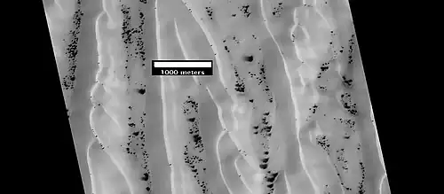 Dunes and defrosting spots in Richardson Crater, as seen by HiRISE.  It is thought that films of liquid water sometimes exist in and around the dark spots.