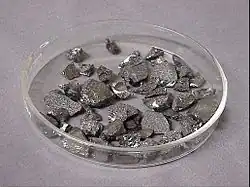 Small chips of lustrous gray metal in a glass dish
