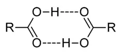 This image illustrates how two carboxylic acids, C O O H, can associate through mutual hydrogen bonds. The hydroxyl portion O H of each molecule forms a hydrogen bond to the carbonyl portion C O of the other.