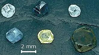 Six non-faceted diamond crystals of 2–3&nbsp;mm (0.079–0.118&nbsp;in) size; they are yellow, green-yellow, green-blue, light-blue, light-blue and dark blue.