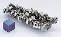 Niobium crystals and a 1&nbsp;cm3 anodized niobium cube for comparison