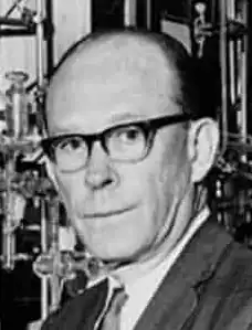 The head of a man wearing glasses, looking at the camera