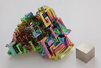 Bismuth in crystalline form, with a very thin oxidation layer, and a 1&nbsp;cm3 bismuth cube