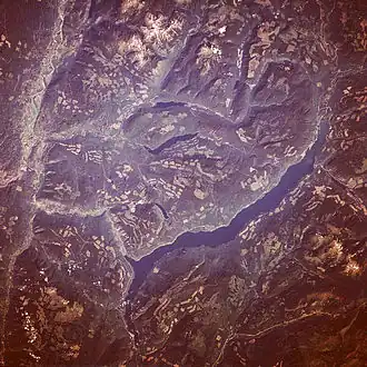 A satellite image of a long, thin lake, surrounded by ridges