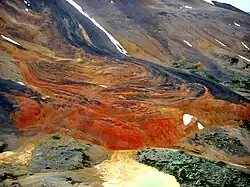 A windswept mountainside with red-orange rock