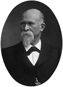 Portrait of Franz König, a Victorian man with a beard and moustache, wearing a black jacket, white shirt, black tie