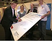 Gavin Hastings is pictured signing a large Parkinson's donation pledge