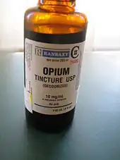 Orange transparent bottle labelled "opium tincture USP (deodorized)." There is a warning label declaring the product to be poisonous.