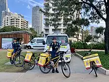 2 Paramedics with bicycles that have large packs on the rear, carrying emergency equipment.