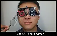 a patient wearing trial frame while doing test for astigmatism