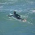 A surfer paddling.
