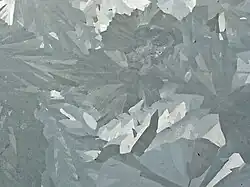 Merged elongated crystals of various shades of gray.