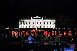 Demonstrators hold up red-lit letters that read PROTECT MUELLER in front of the White House