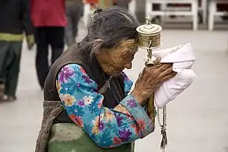 Tibetan woman with a prayer wheel praying