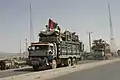 Refugiații afgani care se întorc din Pakistan cu un steag tricolor afgan pe camion (2004)
