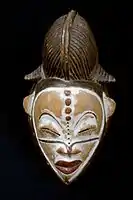 Mască ce era purtată de liderul societății secrete a femeilor. Era purtat în timpul dansului ritualic, în combinație cu un covor de dans confecționat din fibre de plante. Masca reprezintă spiritul unui strămoș sau al unui tutore. Culoarea albă a feței este, de asemenea, tipică lumii spiritului. Culoarea roșie aprinsă a gurii ar trebui să descurajeze spiritele. Spiritele celor decedați vin sub formă de dansatori cu măști în sate pentru a vizita cei vii și ca să corecteze problemele. Deci ele servesc ca un mecanism de aplicare a legilor. Persoanele mascate dansau pe în timpul funeraliilor publice și al altor ceremonii. Stilul în care a fost făcută frizura arată că aceasta este o femeie.