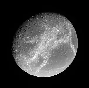 Wispy terrain on Dione's trailing hemisphere. The Eurotas (top) and Palatine Chasmata run from upper right to lower left; the Padua Chasmata are near vertical at right, and the Carthage Fossae horizontal at left. The crater Cassandra and its ray system are at lower right.