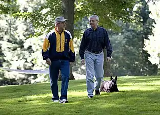 Președintele George W. Bush și șeful de cabinet de la Casa Albă Josh Bolten se plimbă împreună cu câinele președintelui Barney la Camp David, 21 iulie 2007.