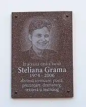 Placă de marmură cu chip de femeie imprimat, și cu textul „În această casă a locuit Steliana Grama, 1974–2006, distinsă scriitoare, poetă, prozatoare, dramaturg, textieră și teatrolog”