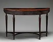 Masă de perete cu multe frunze de acantă și două bucranii; de Robert Adam; circa 1780 cu adăugări ulterioare; mahon; per ansamblu: 88,6 × 141,3 × 57,1 cm; Muzeul Metropolitan de Artă