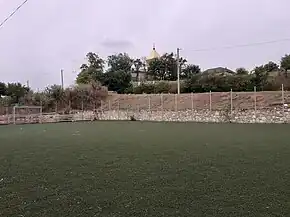 Terenul de minifotbal din localitate, biserica în fundal.
