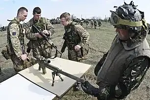 Studierea reciprocă a armamentului individual: 2 soldați britanici la stânga, un soldat român la dreapta (Smârdan, 2015)