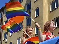 Tinere fluturând steagul-curcubeu în timpul paradei LGBT din Stockholm (2013)