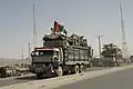 Refugiații afgani care se întorc din Pakistan cu un steag tricolor afgan pe camion (2004)
