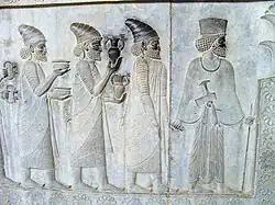 Relief din Persepolis (Iran) care înfățișează oameni care duc blouri și amfore