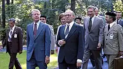 Carter, Begin, and Brzezinski walking together outside.