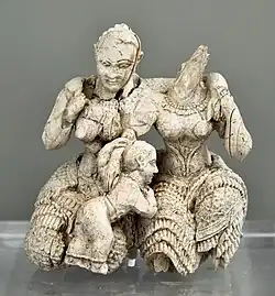 Două femei cu un copil; 1400-1300 î.Hr.; fildeș; înălțime: 7.8 cm; Muzeul Național de Arheologie (Atena)