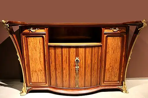 Materiale exotice și ornamente: dulap din lemn de mahon și amourette, decorat cu nuferi de bronz aurit, de Louis Majorelle (1905–1908)